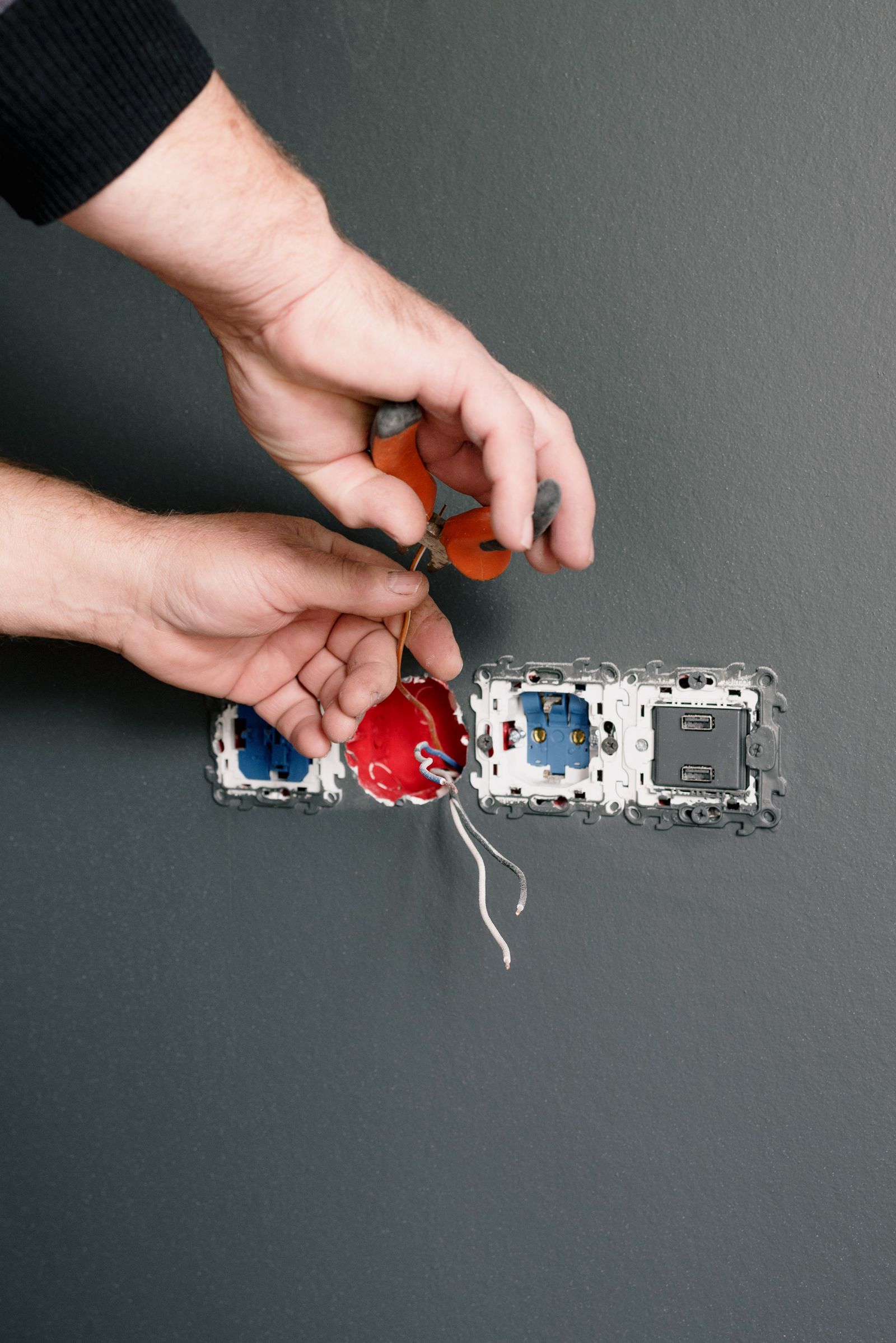 Electrician repairing a power socket with pliers in daylight