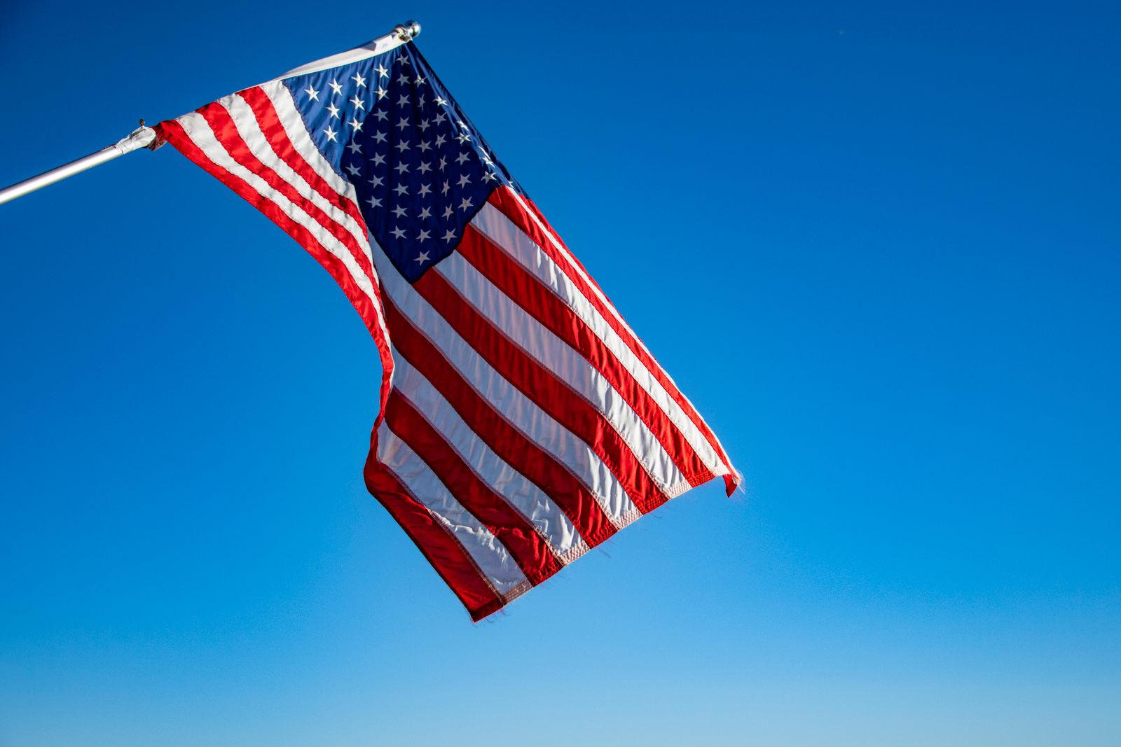 American flag waving on a flagpole against a clear blue sky