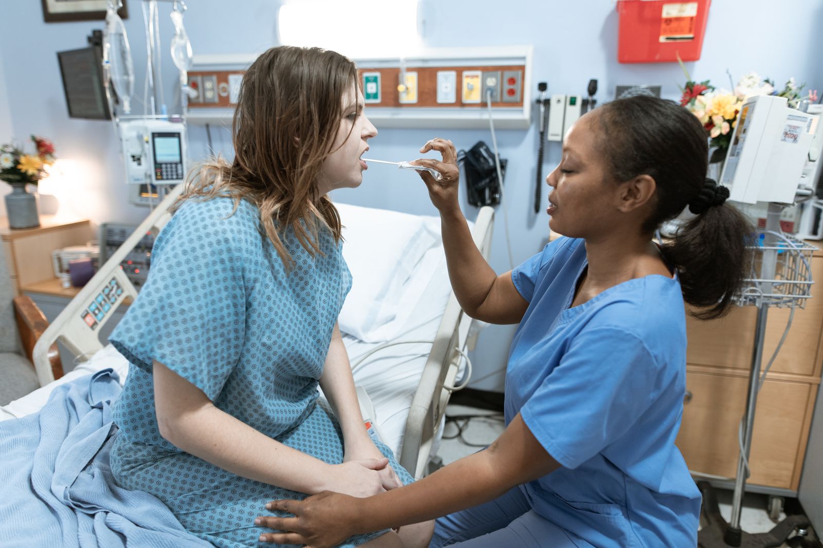 Nurse in scrubs taking a sample from a patient in a hospital ward