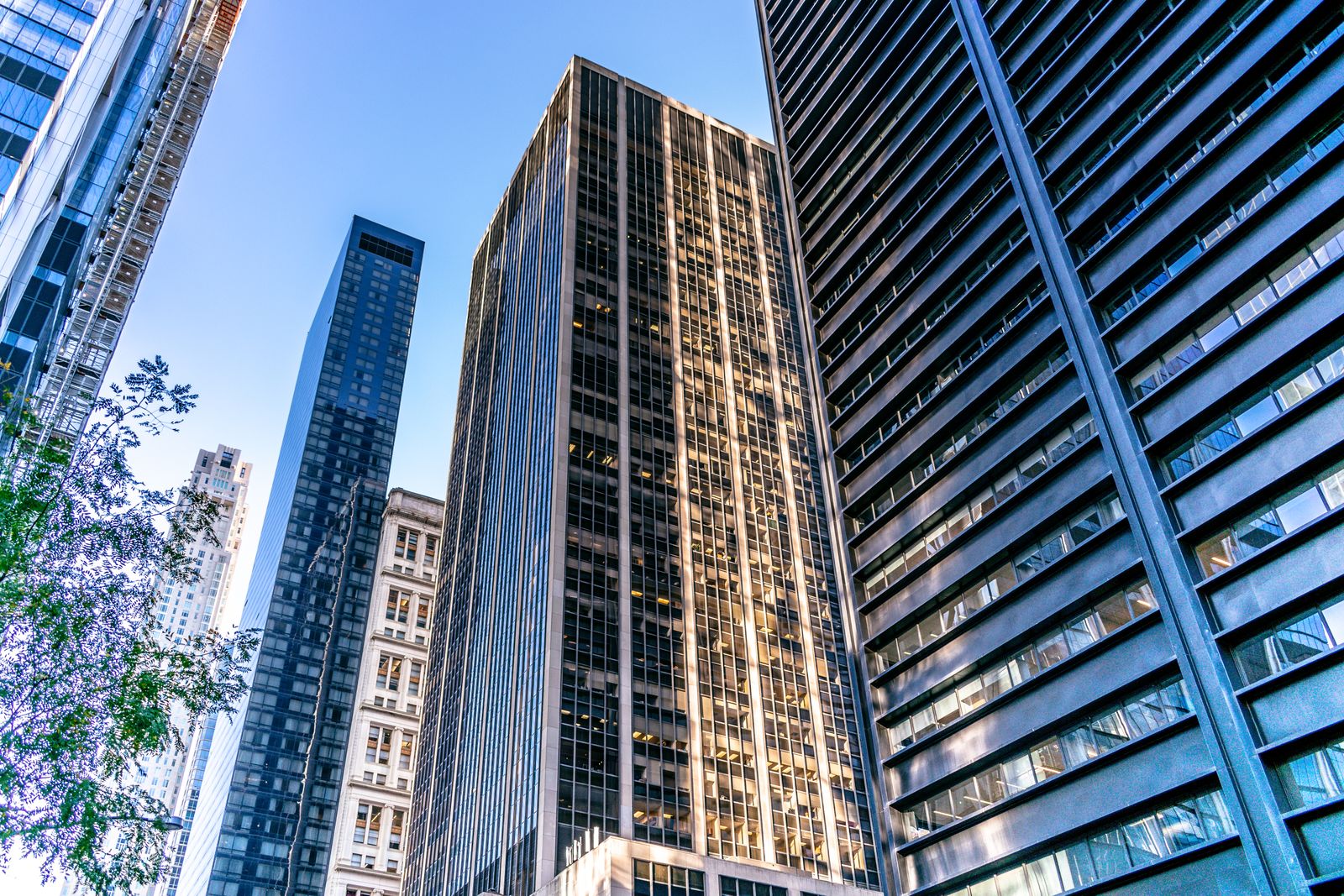 Manhattan high-rise buildings photographed from below under a blue sky