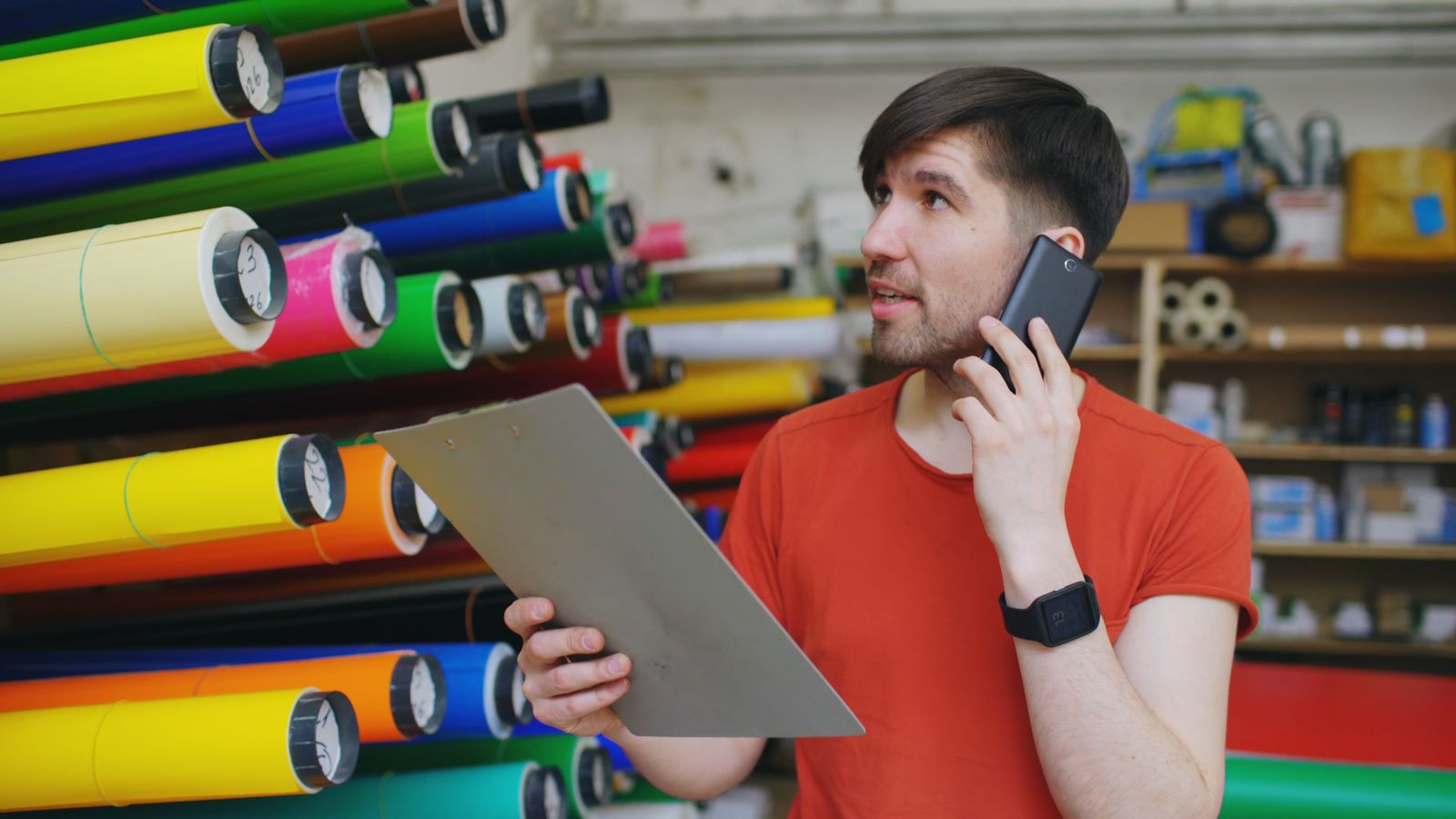 Warehouse worker checking their phone while holding a clipboard between tasks